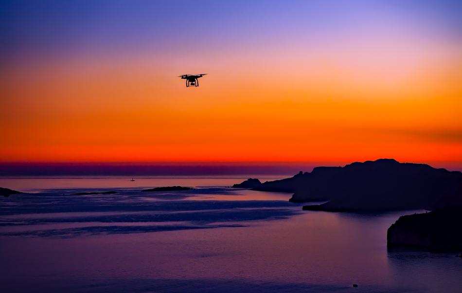 drone flies over the blue ocean against the background of a colorful sunset