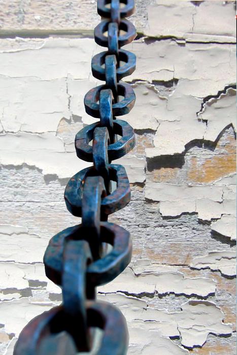 Close-up of the blue, steel chain, near the old wall