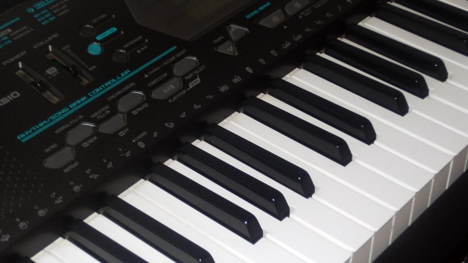 Close-up of the white and black keys of the electronic piano, with the black and turquoise dashboard