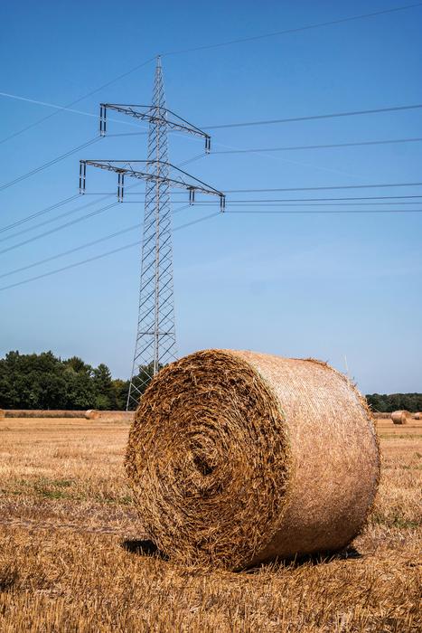 round haystack against the background of a high-voltage tower