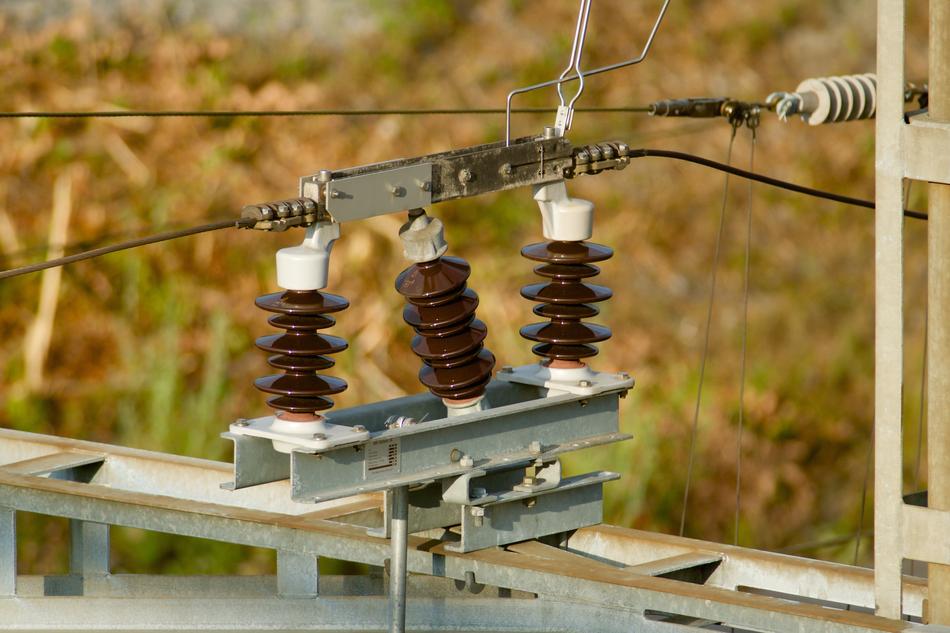 Brown insulators with cables, near the colorful field