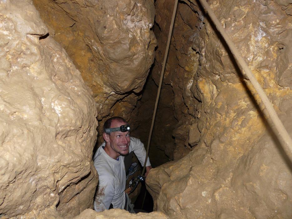 a man with a flashlight on his head in a cave