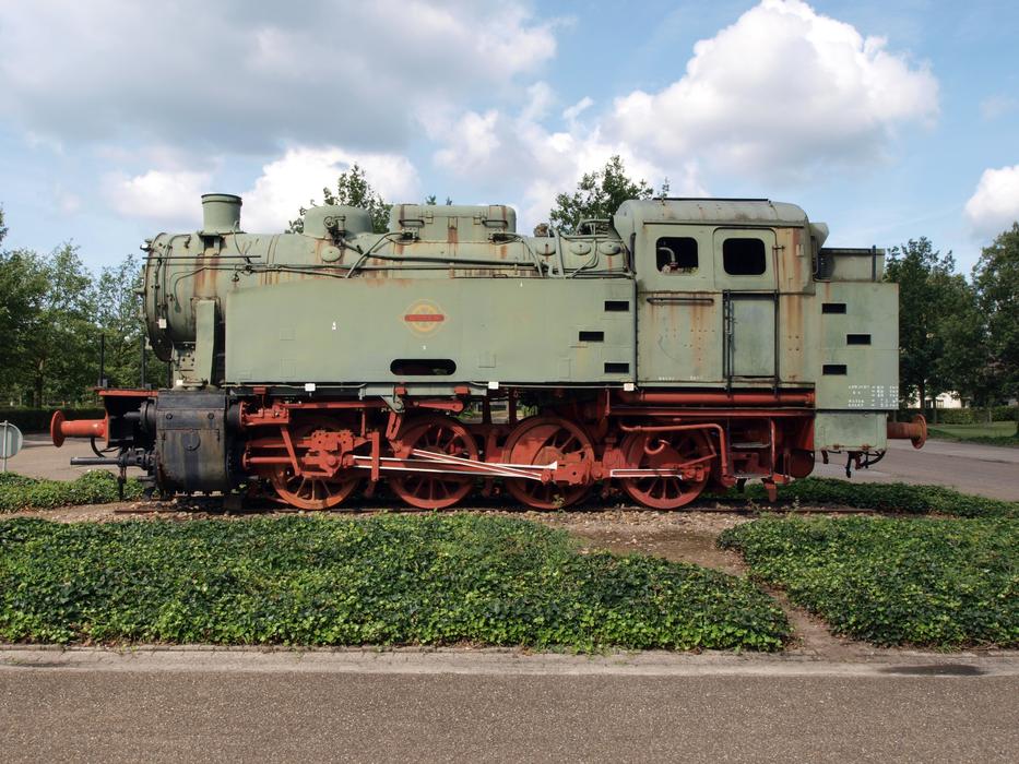 Green and red, rusty Krupp locomotive among the green grass