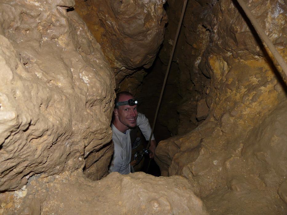 Smiling man, with the head lamp, in the cave, with the darkness