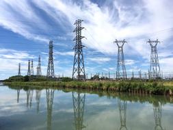 Electricity towers on the beautiful shore of the channel, under blue sky with white clouds