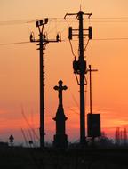 Silhouettes of the power lines against the background of a beautiful, pink-orange evening sky