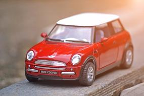 red mini cooper model stands on wooden railing