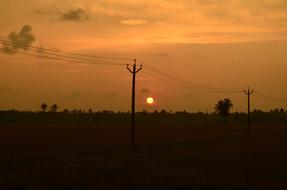 Beautiful landscape with the silhouettes of the power lines, at beautiful and colorful dusk in the evening