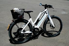 Beautiful, white, turquoise and black bike with the basket on the asphalt