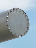 Close-up of a ,eta; tube with rivets, at blue sky with white clouds on background