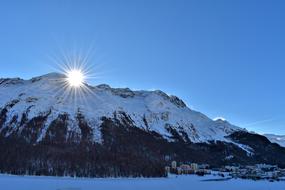 bright sun over a snow-capped mountain peak