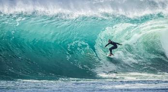 surfer on a high turquoise wave of the ocean