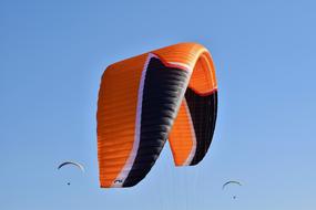 Paragliding, orange and black wing at blue sky close up