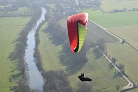 paraglider flying over green fields in France, Normandy