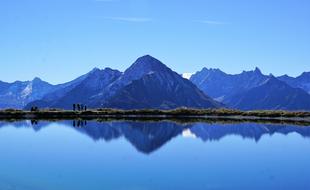 mountains are reflected in the blue water of the lake