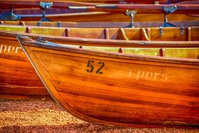 Colorful, wooden rowing boats, with the signs and numbers, on the shore of the lake, in light