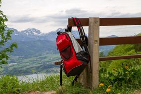 sporty red backpack hanging on a wooden bench