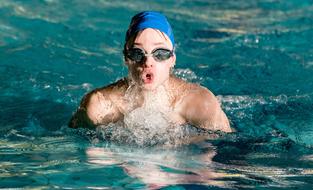 swimmer emerges and takes a breath in the water