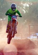 motorcyclist is jumping over obstacle in competition