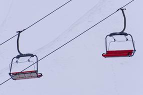 empty Ski Lift chairs on a wires at snowy mountain side