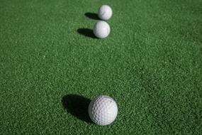 Beautiful, white golf ball in light, with the shadows, on the green grass