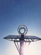 Low angle shot of the basketball net, in sunlight, under the blue sky, in summer