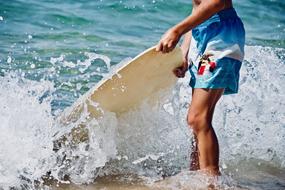 Child stands with surfboard at sea