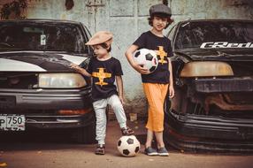 Children with black and white ball among the retro cars