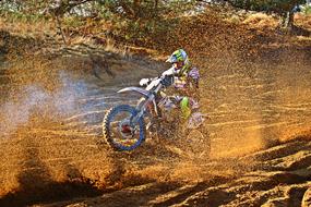 Colorful rider on the dirtbike, on the landscape, on the Enduro competition, in light