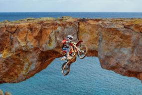 man jumping on Motorcycle at rock on seaside
