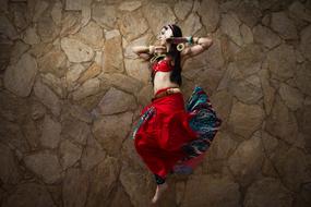 young Woman Jumping at stone wall, oriental Dance