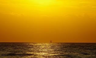 sailboat in the ocean against the yellow sky