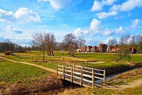 Bridge, among the beautiful and colorful fields, with the trees, in Holland, under the blue sky with white clouds