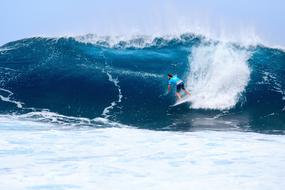 man sliding down high wave, surfing