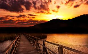 wooden pier on the lake at orange dusk