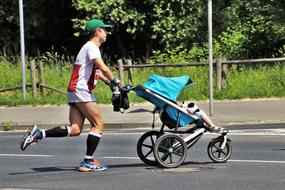 Cross country skier father, with the child, on the road, near the green plants