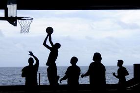 silhouettes of a group of people playing basketball on the background of the sea