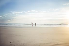 photo of two surfers on the horizon