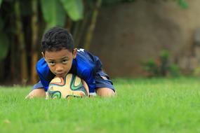 black boy lies on a soccer ball