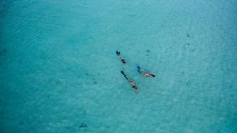 three people swim in the azure ocean