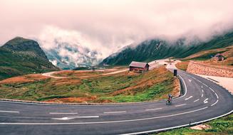 Beautiful landscape of the road, with the cycler, among the colorful and beautiful mountains in snow and clouds, in Austria