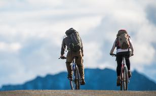 two tourists on bicycles go to the mountains