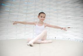 young ballerina against a white wicker wall