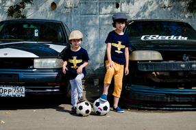 boys with soccer balls near black cars