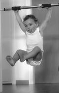 Black and white photo of a cute child, doing exercises on the abdominal trainer