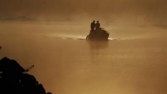 Silhouettes of the people, on the boat tour, on the beautiful waterscape, in yellow sunrise