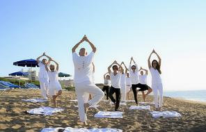 People in white and black clothing, practicing yoga on the beautiful sandy beach