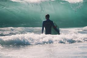 surfer stands in Sea in front of wave
