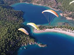 three paragliders high above a tropical islan