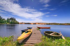 kayaks and fishing boat at the wooden pier on the lake